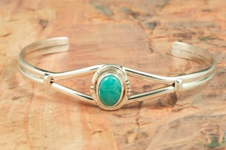 Genuine Royston Turquoise set in Sterling Silver Bracelet. The Royston Turquoise Mine was originally known as the Royal Blue Mine. It produces Turquoise that has a mixture of blues and greens in the same formation. The Royston Turquoise Mine is located in Nye County, Nevada. Created by Navajo Artist Lucy Valencia. Signed L. J. by the artist.